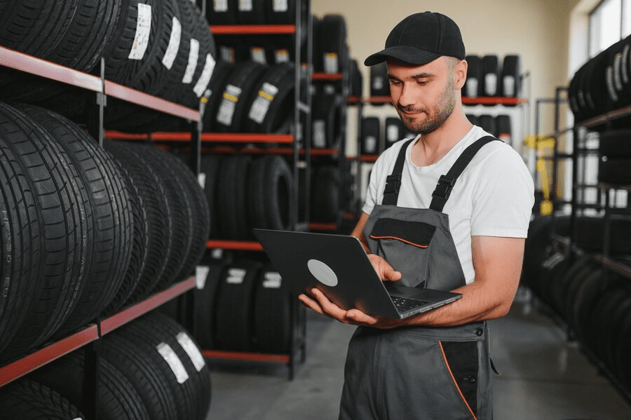 Confident mechanic man checking characteristics of tyre in auto service shop