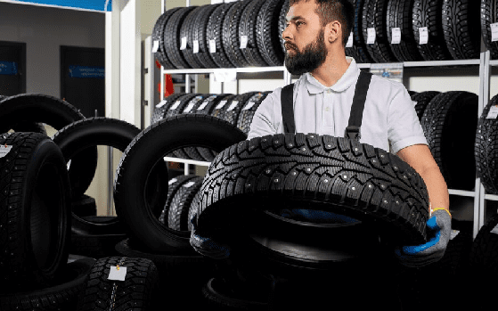 Mechanic holding a tire and showing wheel tires at car repair service